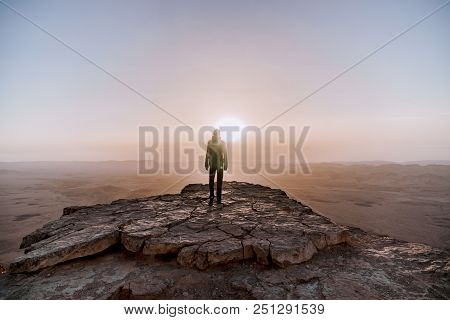 Alone Man In Israel Negev Desert Admires The View Of Sunrise. Young Male Person Stands On The Edge O