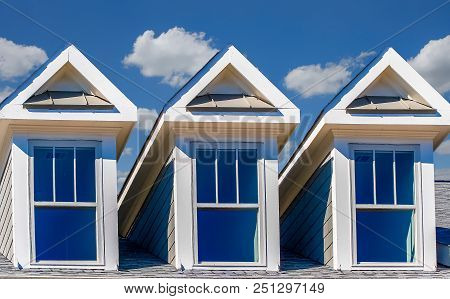A Roof Line With Three Dormers Against A Blue Sky