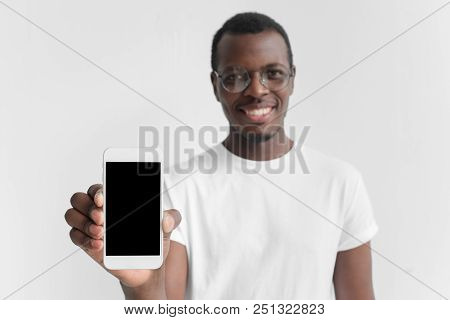 Closeup Of Young Afrcian American Man Smiling Isolated On Grey Background, Holding And Showing Verti