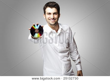 portret przystojny młody mężczyzna trzyma cd na szarym tle