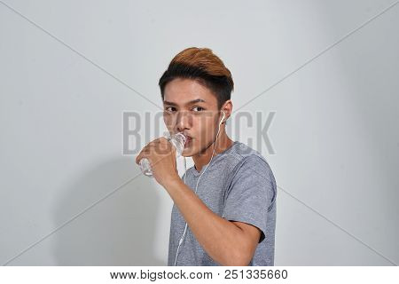 Handsome Young Muscular Sportsman Holding A Bottle Of Water And Listening To Music