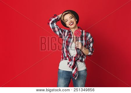 Happy Hipster Girl With Lollipop At Red Studio Background, Copy Space