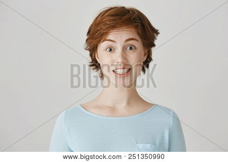 Studio Portrait Of Attractive Caucasian Female With Red Hair And Freckles Feeling Awkward, Lifting E