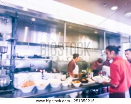 Blurred Background Chef Preparing For Lunch Service And Waiter Taking Ordered Dishes