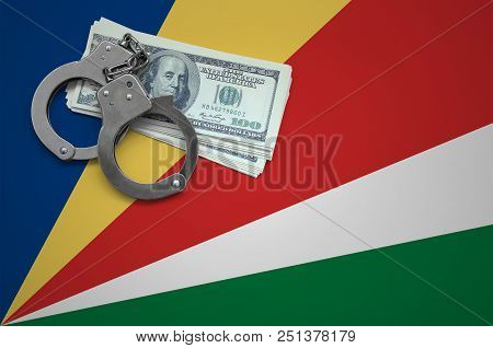 Seychelles Flag  With Handcuffs And A Bundle Of Dollars. The Concept Of Breaking The Law And Thieves