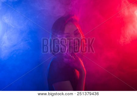 Portrait Of Asian Woman Smoking Vape Or E-cigarette In Neon Light At Black Background