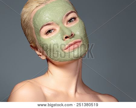 Beautiful Woman Applying Green Facial Mask. Beauty Treatments. Close-up Portrait Of Spa Girl Apply C
