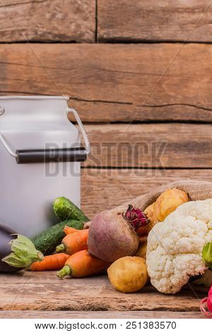 Different Vegetables And Enamelware Milk Churn. Still Life. Wooden Desk Table Background.