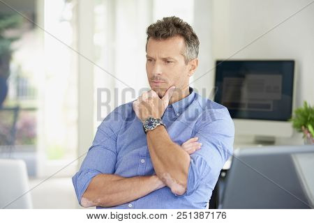 Thinking Businessman Sitting At Office Desk And Using His Laptop