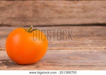 Yellow Tomato On Wood And Copyspace. Close Up. Old Wooden Table.