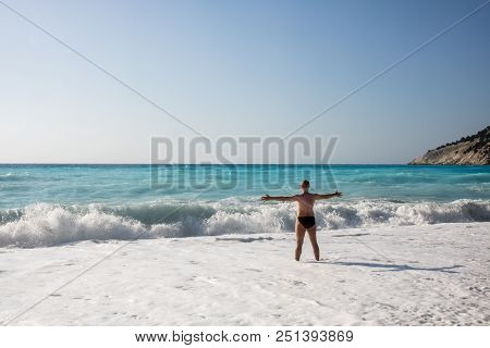 Man Chasing The Waves On Myrtos Beach, Island Kefalonia, Greece