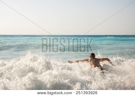 Man Chasing The Waves On Myrtos Beach, Island Kefalonia, Greece