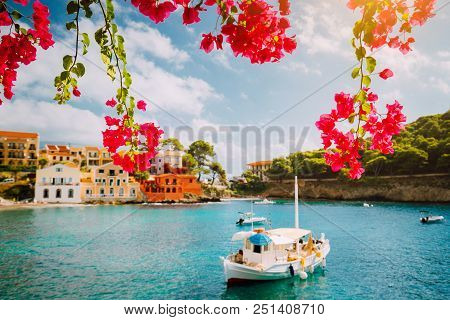 Kefalonia Greece Assos Village, Fishing Boat In Tranquil Bay And Magenta Fuchsia Blossom. Picturesqu