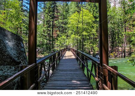 Crossing A Wooden Bridge Over The Raging King River Into The Forest Of Kings Canyon National Park
