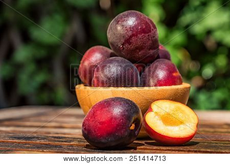 Close Up Fresh Plumcot, Interspecific Plums Variety In Wooden Bowl On Wooden Table. Selective Focus,
