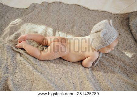 Naked Newborn Baby Lying On His Tummy In A Knitted Hat. Little Boy On Grey Background. Advertising P