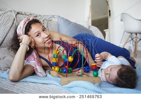 Attractive Cheerul Young Hispanic Nurse Babysitting Boy Toddler, Playing Games With Him. Happy Mothe