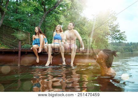 Enjoying Forest Party With Friends. Group Of Beautiful Happy Young Men And Girls Swimming At The Riv