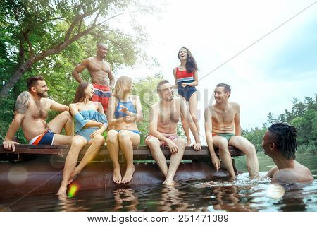 Enjoying Forest Party With Friends. Group Of Beautiful Happy Young Men And Girls Swimming At The Riv