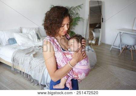 Casually Dressed Young Mixed Race Woman With Wavy Hair Spending Day At Home, Cradling Her Infant Chi