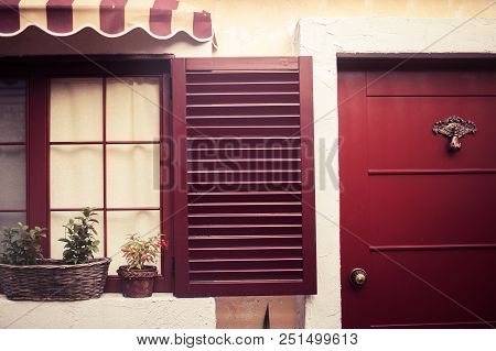 Cozy House With Red Wooden Shutters And Pots With Flowers On Windows Captured In Tirana City Center