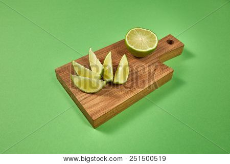 Healthy food concept. Natural organic citrus fruit - slices of of green organic lime on a wooden board on green with copy space .