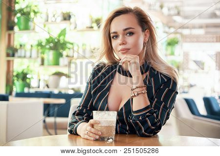 A Young, Successful Woman Having A Drink Sitting At A Table In A Modern Cafe While Waiting Her Partn