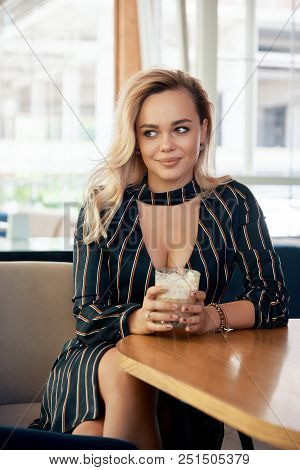 A Young, Successful Woman Having A Drink Sitting At A Table In A Modern Cafe While Waiting Her Partn