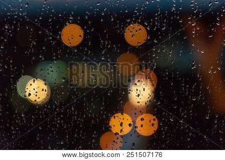 Drops Of Rain On Blue Glass Background. Street Bokeh Lights Out Of Focus. Autumn Abstract Backdrop