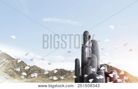 Young Female Doctor With Folder In Hands Satnding On Stone Column