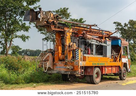 Belathur, Karnataka, India - November 1, 2013: Orange Water Drill Truck Stands Along Rural Road Unde