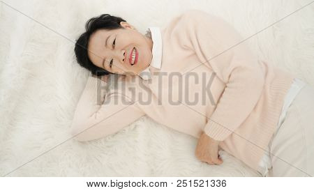 Asian Senior Woman Wear Pink Sweater Sleep On White Fur Bed