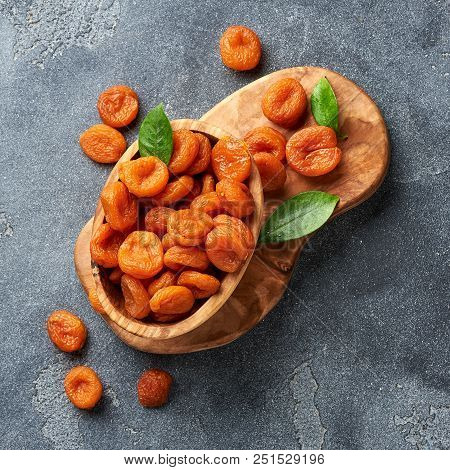 Dried Apricots With Green Leaves On Gray Background. Top View.