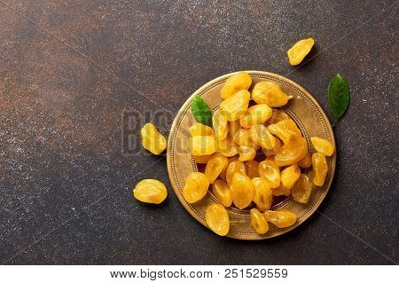 Dried Yellow Kumquat With Green Leaves On Brown Background. Top View.
