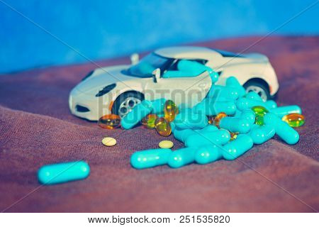 A Child's White Machine Unloads Blue Capsules And Different Tablets On A Brown Surface On A Blue Bac