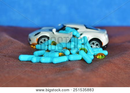 A Child's White Machine Unloads Blue Capsules And Different Tablets On A Brown Surface On A Blue Bac