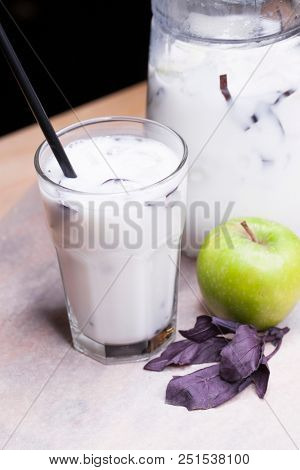 Ayran - liquid drink made from yogurt in ransparent glass cup and green apple