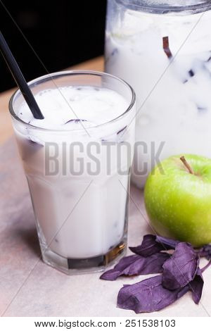Ayran - liquid drink made from yogurt in ransparent glass cup and green apple