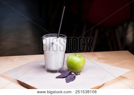 Ayran - liquid drink made from yogurt in ransparent glass cup and green apple