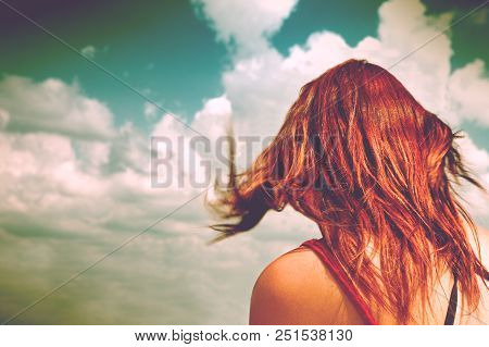 Anonymous Woman With Red Hair And Blue Sky.woman On Her Back With Her Hair Moved By The Air Looking 