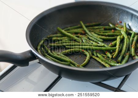 Frozen Green Beans In Frying Pan, Salt, Pepper And Vegetable Oil On Gas Stove