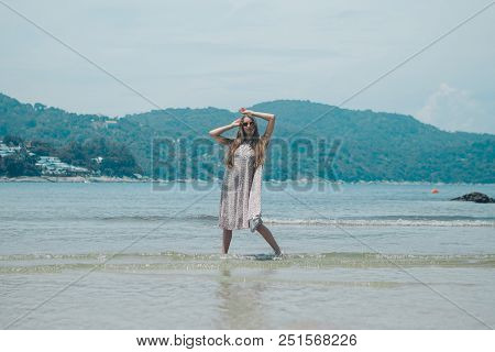 Handsome Girl On The Beach Background. Portrait Of A Woman In White Clothes On The Sea