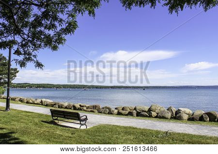 Bench On The Shoreline Of Canandaigua Lake. Beautiful View Across The Lake. Summer In The Finger Lak