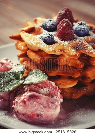 Plate of belgian waffles with ice cream and fresh berries - raspberries and blueberries