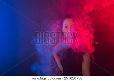Portrait Of Asian Woman Smoking Vape Or E-cigarette In Neon Light At Black Background