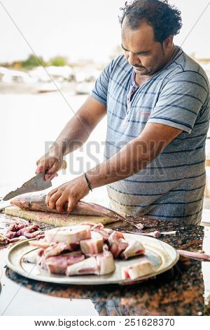 Dibba, Al Fujairah, UAE, November 25, 2016: a local fisherman cleaning fish near Dibba Port, UAE