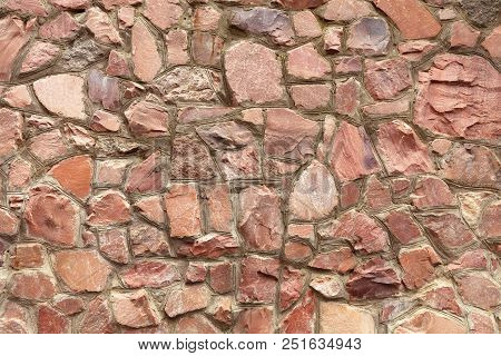 The Wall Is Made Of Natural Coarse Red Granite With Embroidered Borders Of Cement