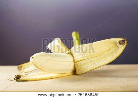 One Whole Fresh Yellow Banana Opened Like A Plane With Grey Gradient Behind