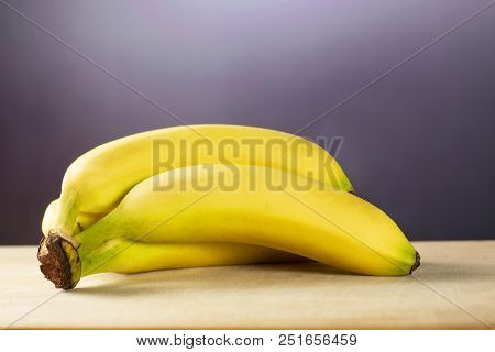 Group Of Five Whole Fresh Yellow Banana One Ripe Cluster With Grey Gradient Behind