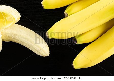 Lot Of Whole Fresh Yellow Banana And One Opened Flatlay On Black Wood